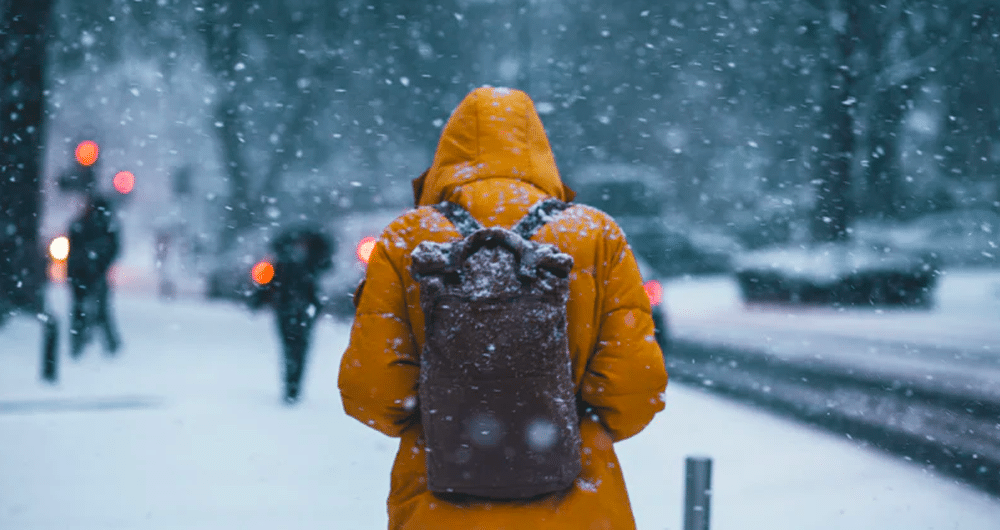 financial-grit person walking in snow wearing jacket