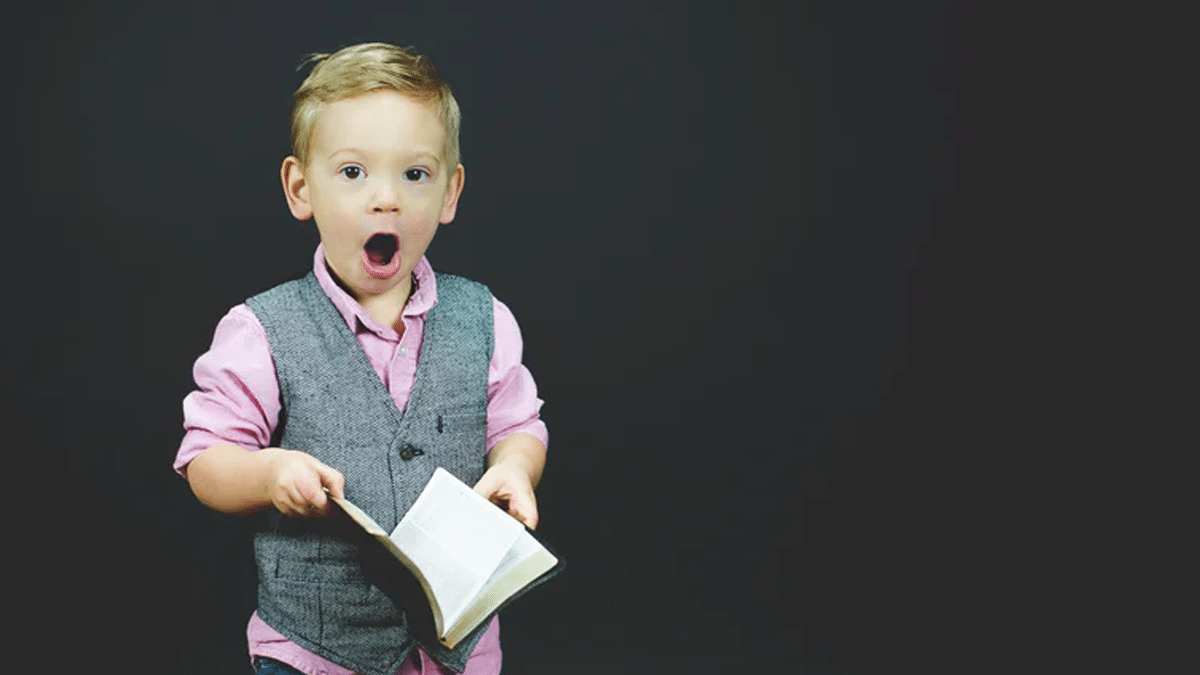 boy holding book looks surprised