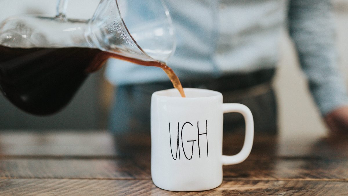 Coffee being poured into a mug with "UGH" written on it.