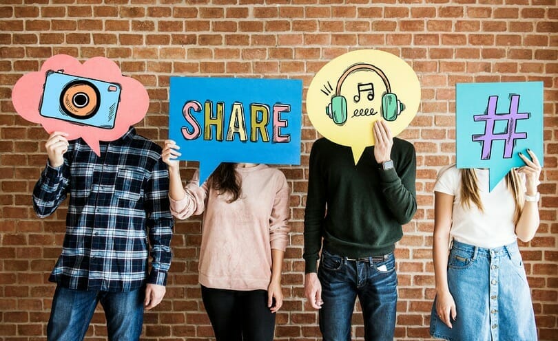 A group of people holding up different social media symbols on signs.