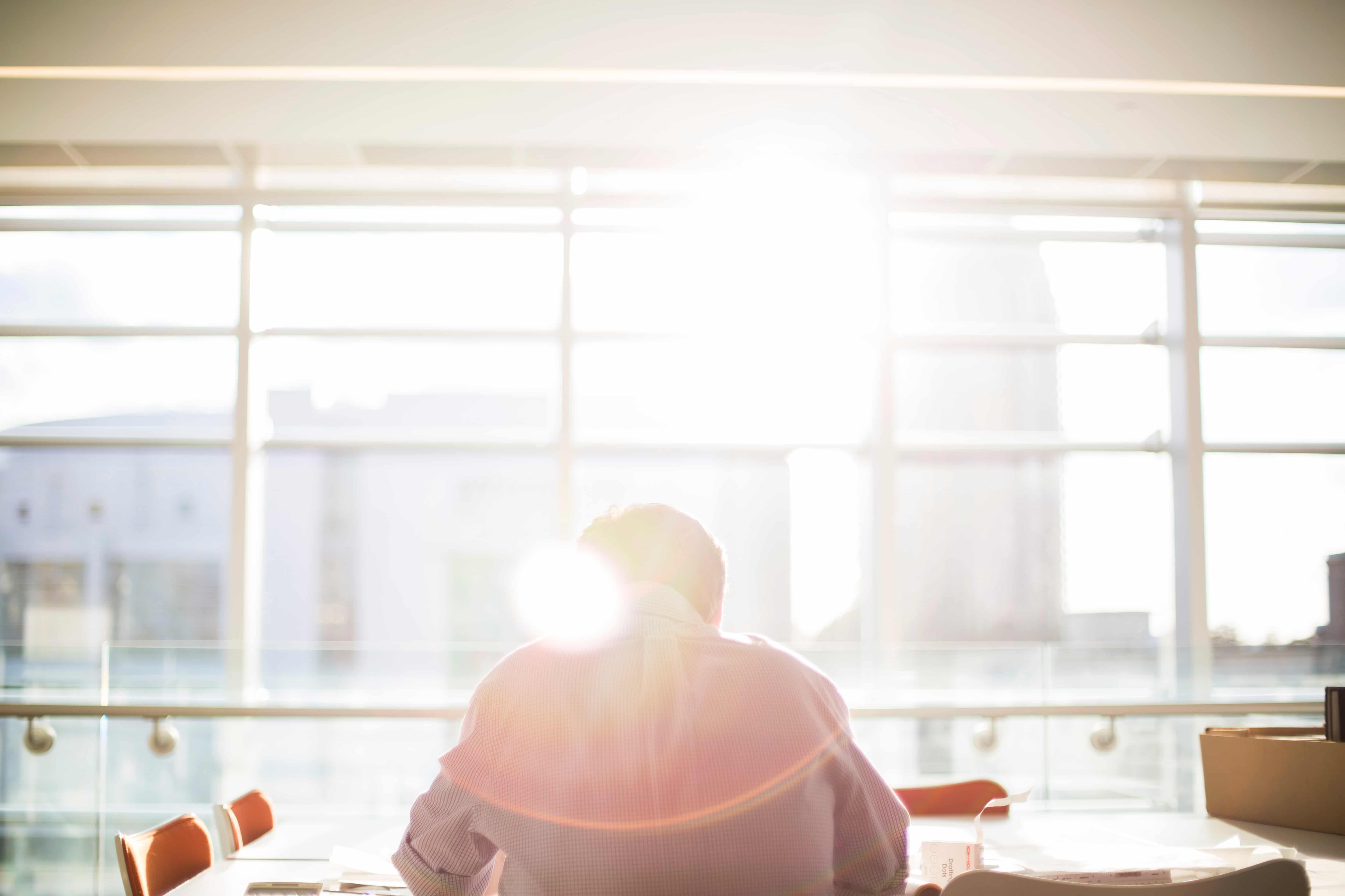 Someone sitting at a table with the sun glaring through a window.