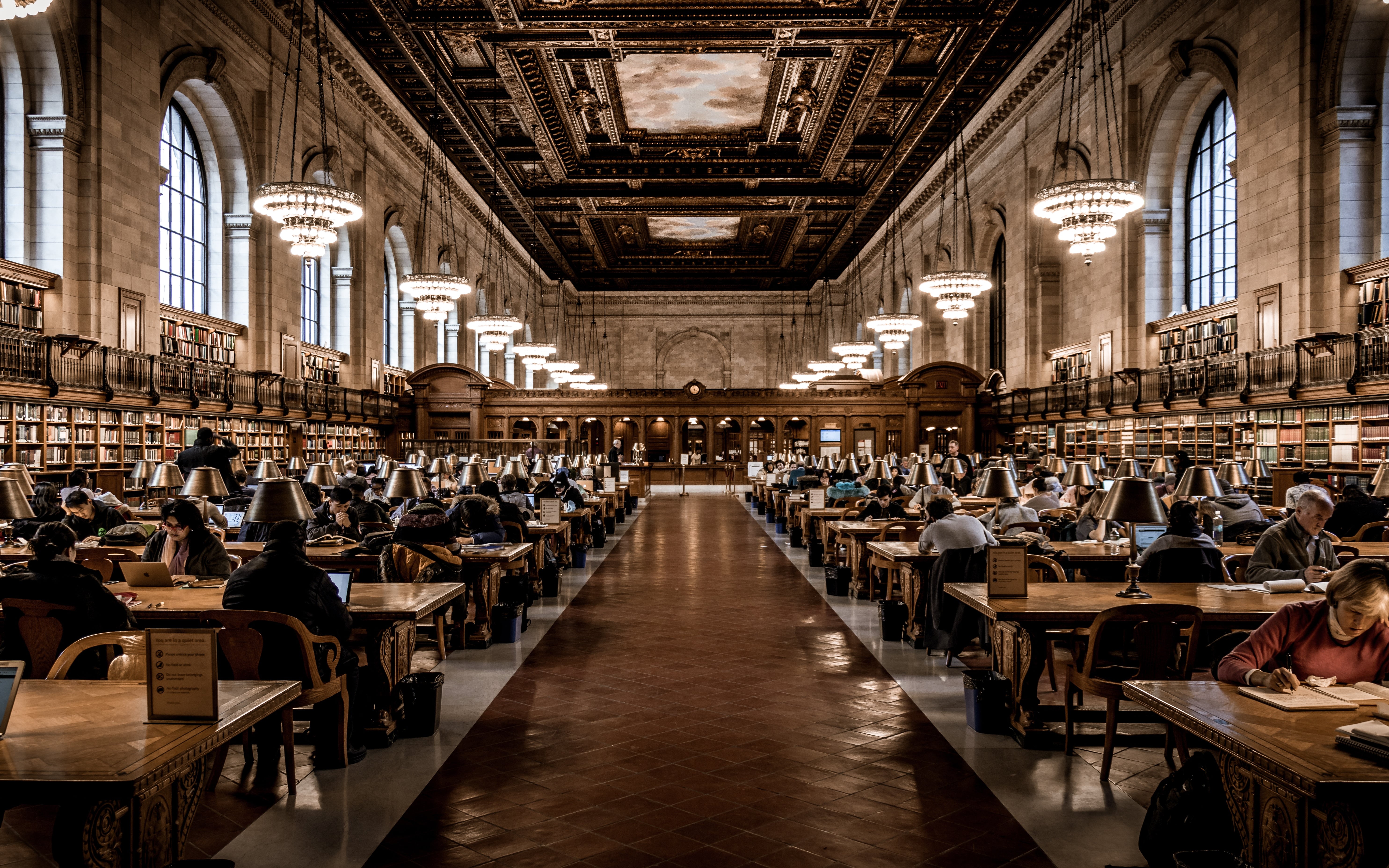 Many people working and reading inside of the New York Public Library.