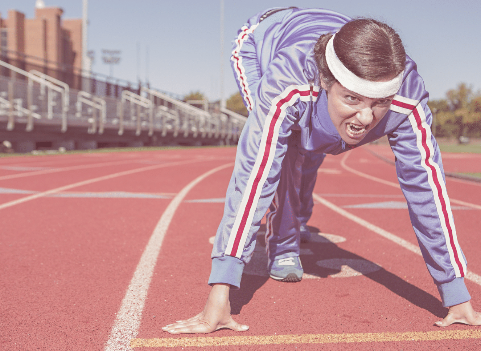 A women at a track starting line, ready to start running.