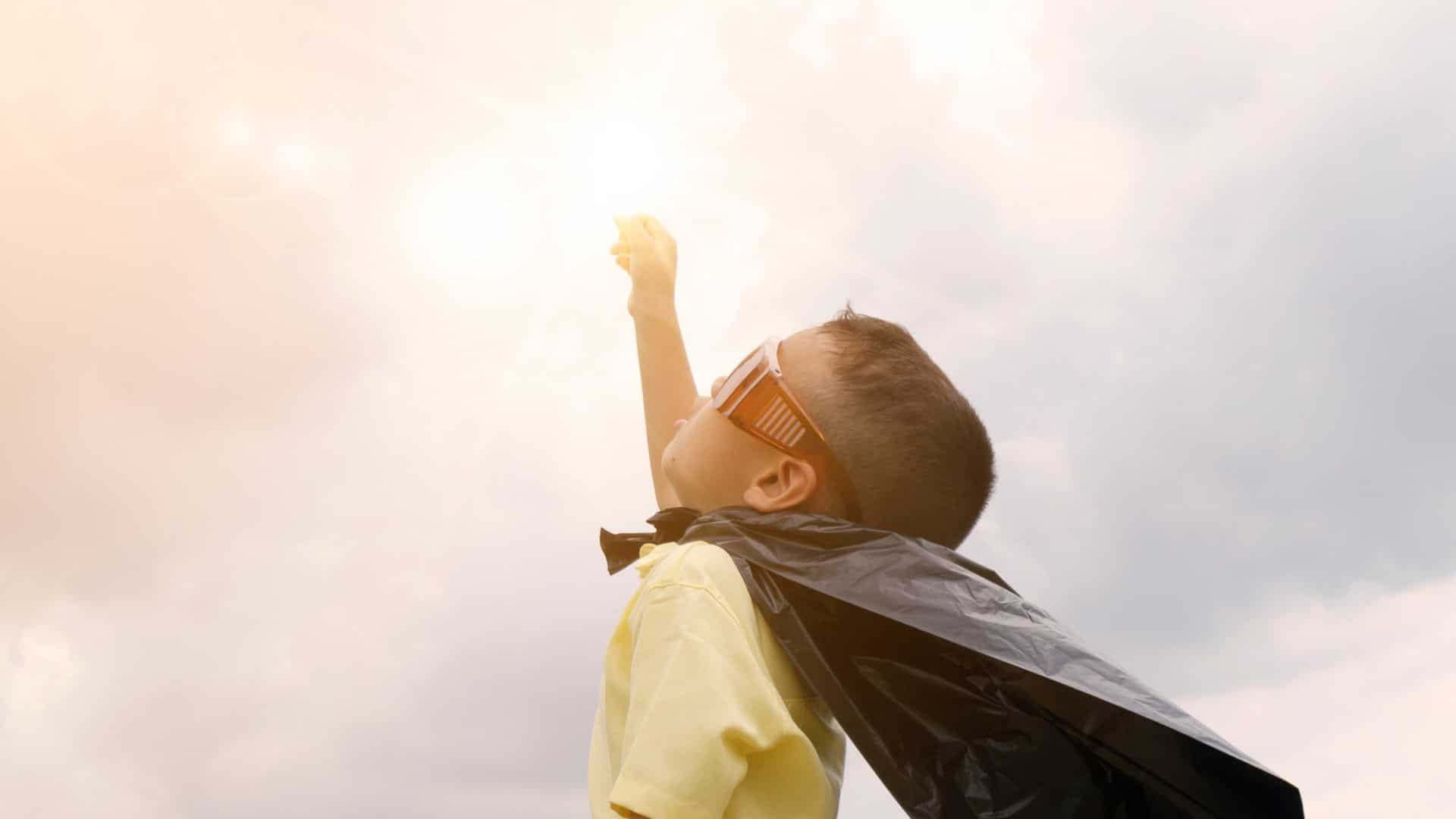 A kid wearing a cape like a superhero.