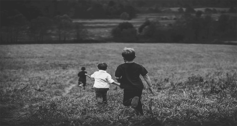 three boys running in a field - making a purchase